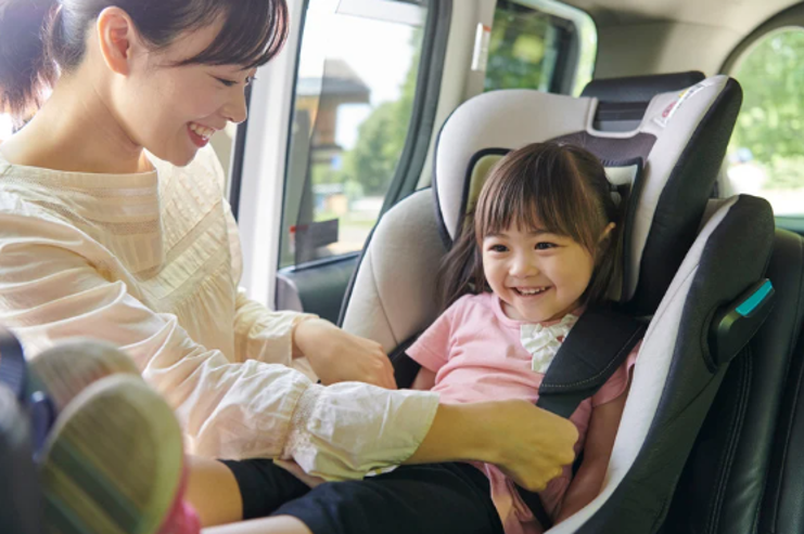 Parent buckling a young child into their car seat.